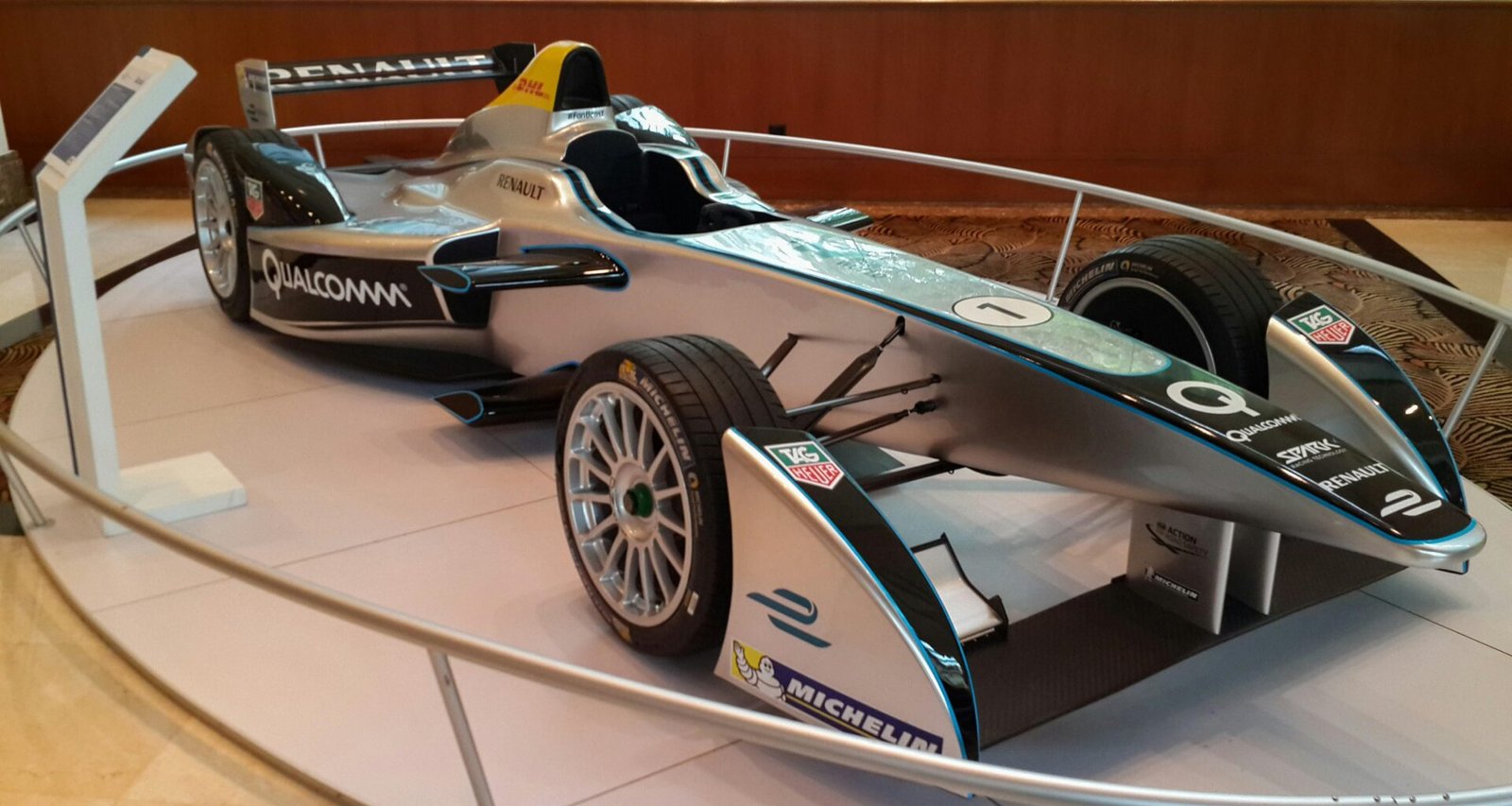 Silberner Formel-E-Rennwagen steht ausgestellt auf einer Motorsportveranstaltung, Elektroauto im Fokus.