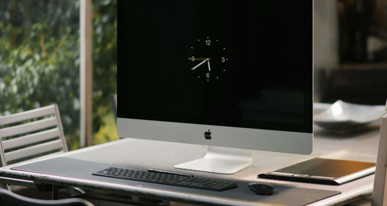 Silberner iMac auf braunem Holzschreibtisch in moderner Büroumgebung, geeignet für technikbezogene Themen