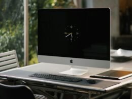 Silberner iMac auf braunem Holztisch, moderner Arbeitsplatz, ideal für Büro oder Homeoffice-Umgebung
