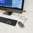 Silberner Apple iMac neben Apple Magic Keyboard und Magic Mouse auf einem Schreibtisch, minimalistisches Tech-Setup