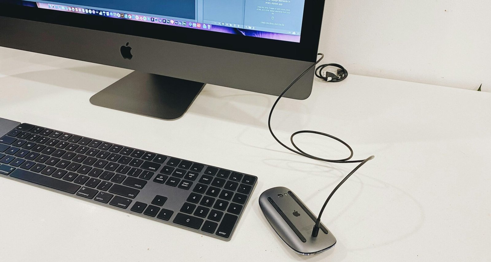 Silberner Apple iMac neben Apple Magic Keyboard und Magic Mouse auf einem Schreibtisch, minimalistisches Tech-Setup