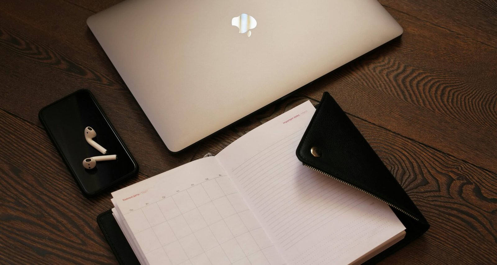 Silbernes MacBook positioniert neben einem schwarzen iPhone 5 auf einem Tisch unter neutralem Licht