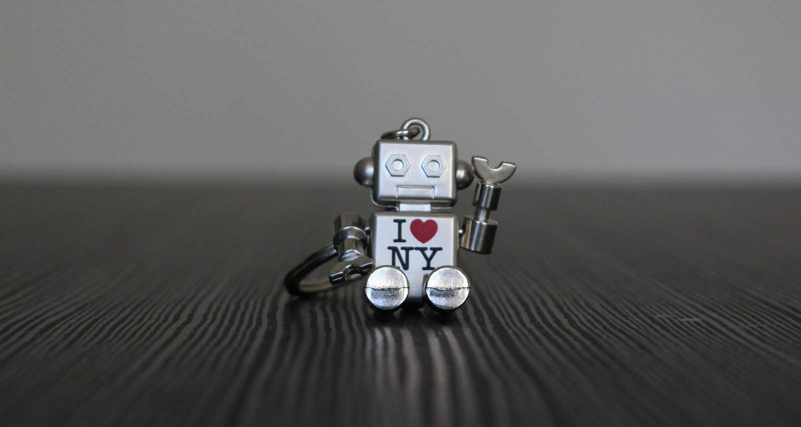 Silberner und schwarzer Roboter als Spielzeug, stehend auf glatter Oberfläche, Vorderansicht mit künstlichen Details