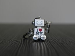 Silberner und schwarzer Roboter als Spielzeug, stehend auf glatter Oberfläche, Vorderansicht mit künstlichen Details