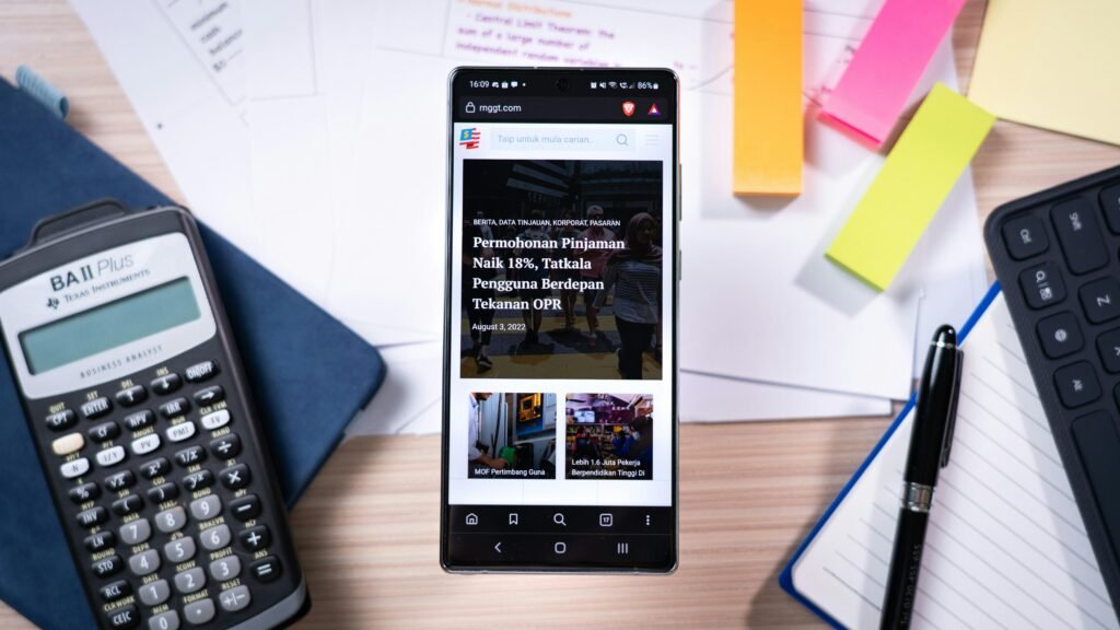 Smartphone liegt auf einem Schreibtisch neben einem Taschenrechner und bunten Haftnotizen, moderner Arbeitsbereich