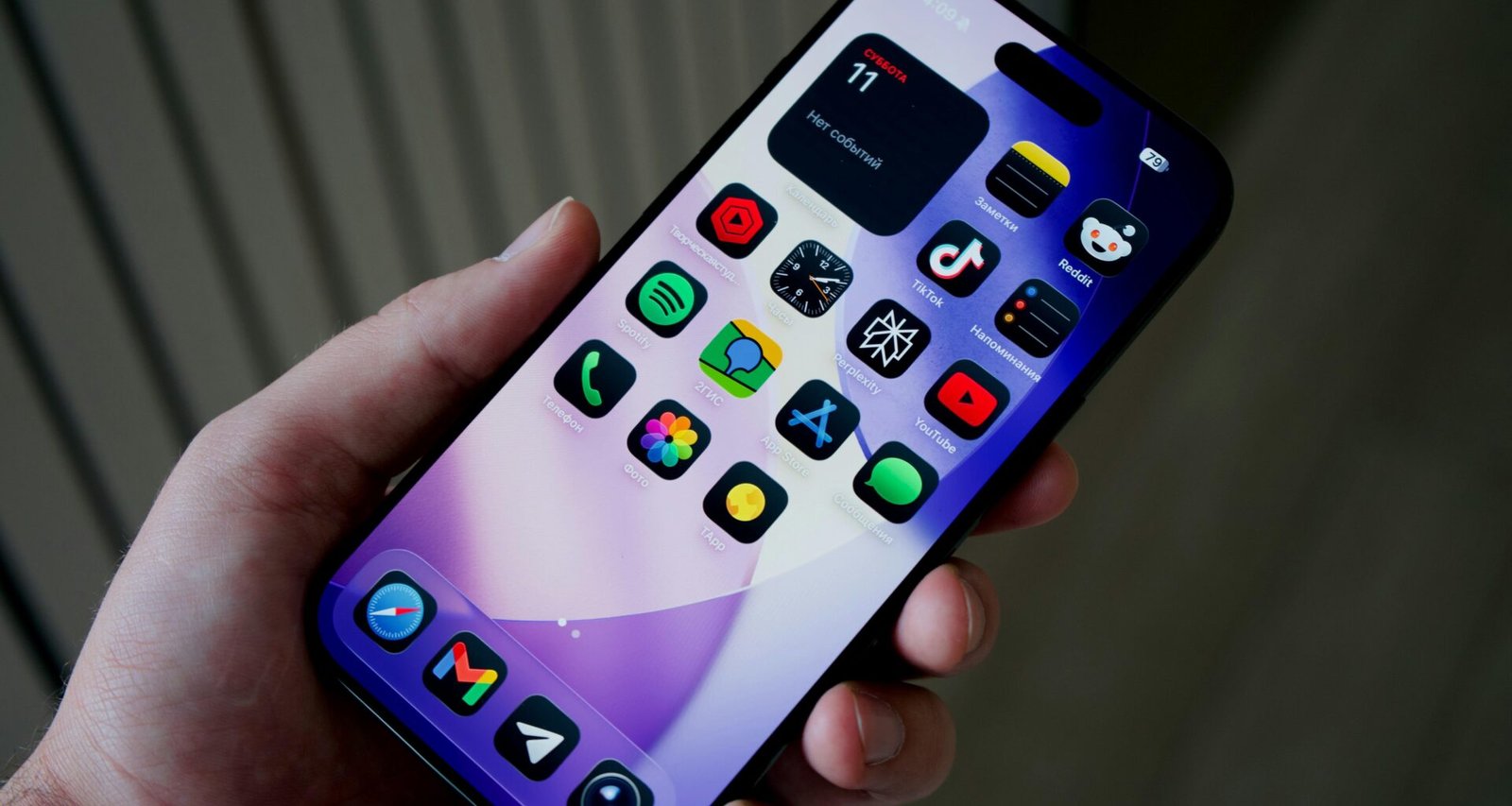 Hand hält ein Smartphone mit vielen verschiedenfarbigen App-Icons auf dem Display in Nahaufnahme