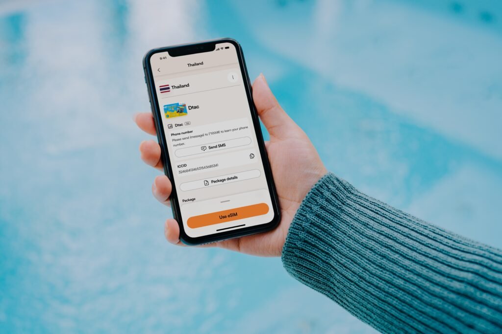 Person hält ein Smartphone in der Hand, auf dem eine Reise-App geöffnet ist, Fokus auf die mobile Anwendung.