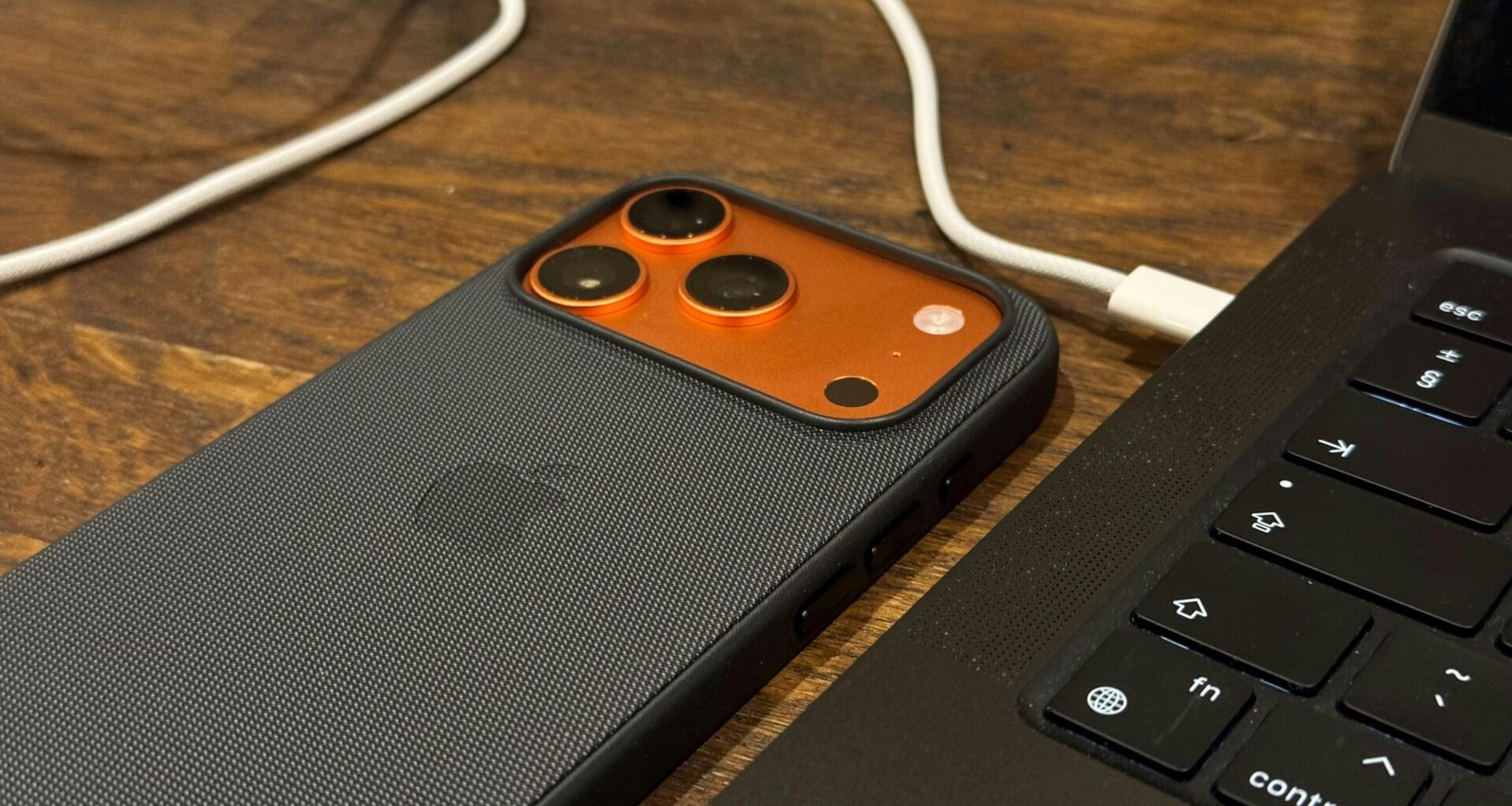 Ein Smartphone wird über ein Kabel mit einem Laptop verbunden. Beide Geräte liegen auf einem Tisch und sind eingeschaltet.