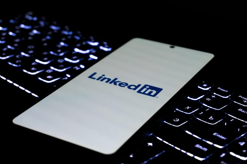 Smartphone mit LinkedIn-Logo liegt auf einer farbig beleuchteten Tastatur, Fokus auf modernes Networking im digitalen Umfeld