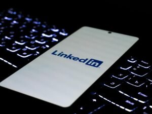 Smartphone mit LinkedIn-Logo liegt auf einer farbig beleuchteten Tastatur, Fokus auf modernes Networking im digitalen Umfeld