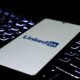 Smartphone mit LinkedIn-Logo liegt auf einer farbig beleuchteten Tastatur, Fokus auf modernes Networking im digitalen Umfeld