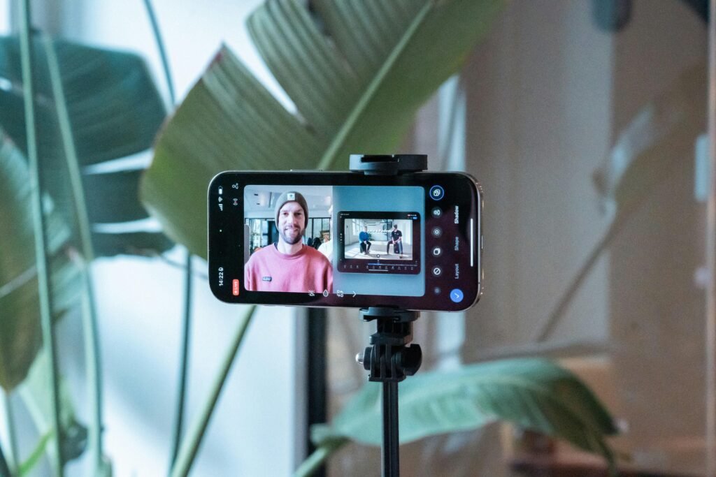 Ein Smartphone filmt einen Mann in einem pinken Hemd, der für ein Video oder Social-Media-Content posiert
