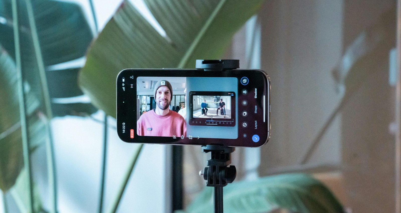 Ein Smartphone filmt einen Mann in einem pinken Hemd, der für ein Video oder Social-Media-Content posiert