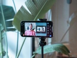 Ein Smartphone filmt einen Mann in einem pinken Hemd, der für ein Video oder Social-Media-Content posiert
