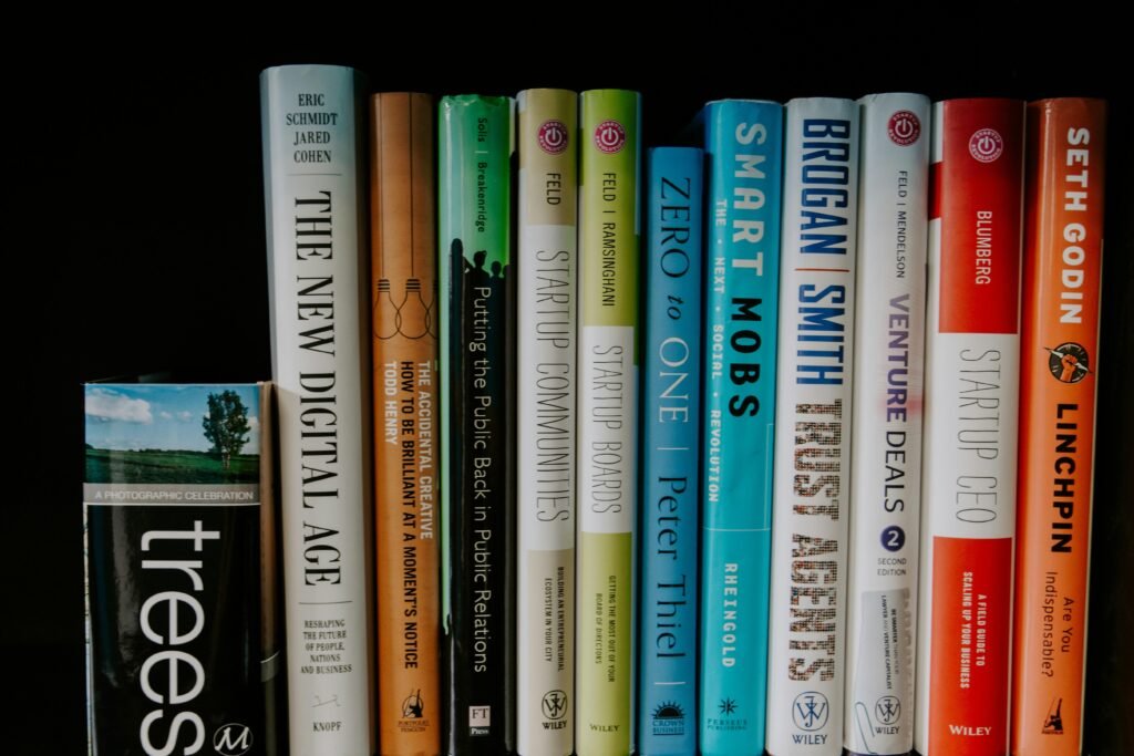 Eine Auswahl verschiedener Bücher liegt auf einem Tisch, geordnet und teils übereinandergestapelt, aufgenommen aus der Vogelperspektive.