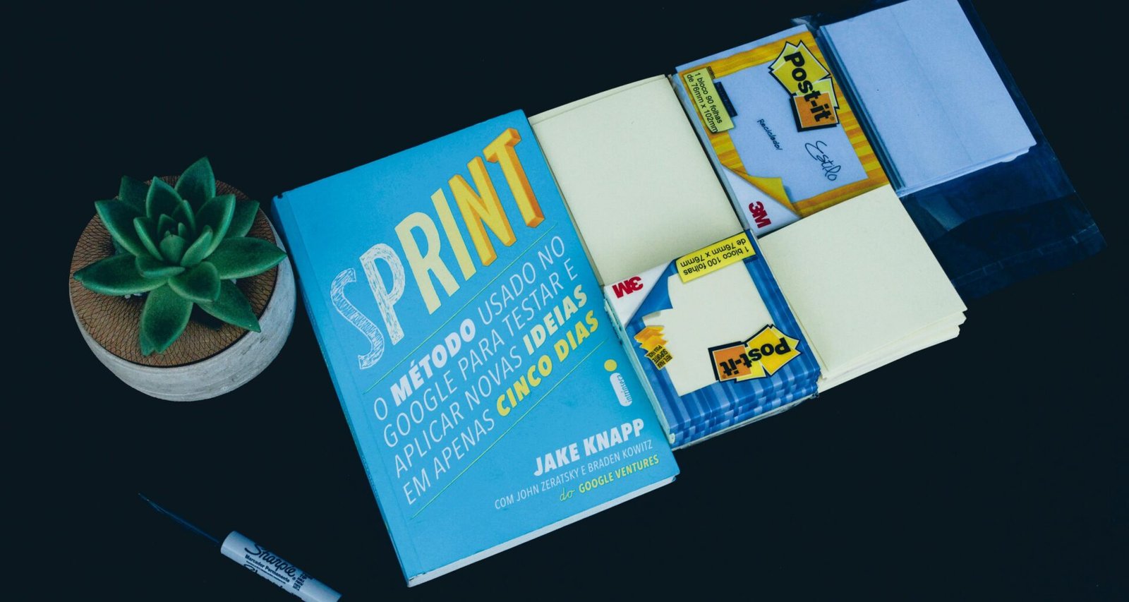 Ein Sprint Buch liegt auf einem Tisch neben einem schwarzen Marker – beide als Tools für agiles Vorgehen im Arbeitsalltag.