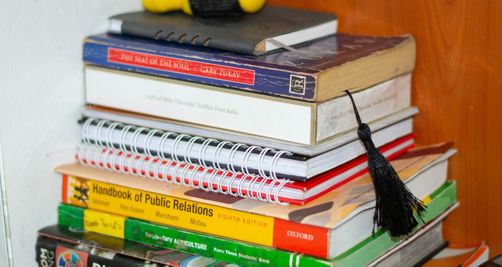 Bücherstapel mit einem gelben Gegenstand obenauf, arrangiert auf einem Tisch in ruhiger Umgebung, fotografiert von Michael Odida.