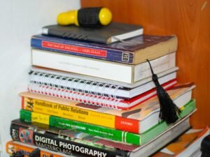 Bücherstapel mit einem gelben Gegenstand obenauf, arrangiert auf einem Tisch in ruhiger Umgebung, fotografiert von Michael Odida.