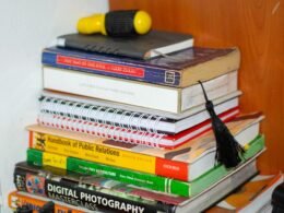 Ein Stapel Bücher liegt übereinander, darauf befindet sich ein gelbes Objekt, fotografiert als Symbol für Wissen und Kreativität