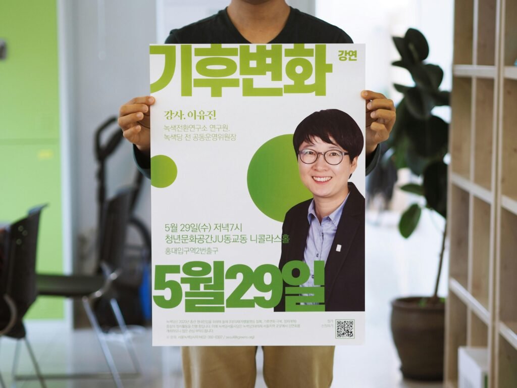 Stehende Person hält ein Poster mit dem Bild eines lächelnden Mannes sowie Texten in koreanischer Schrift
