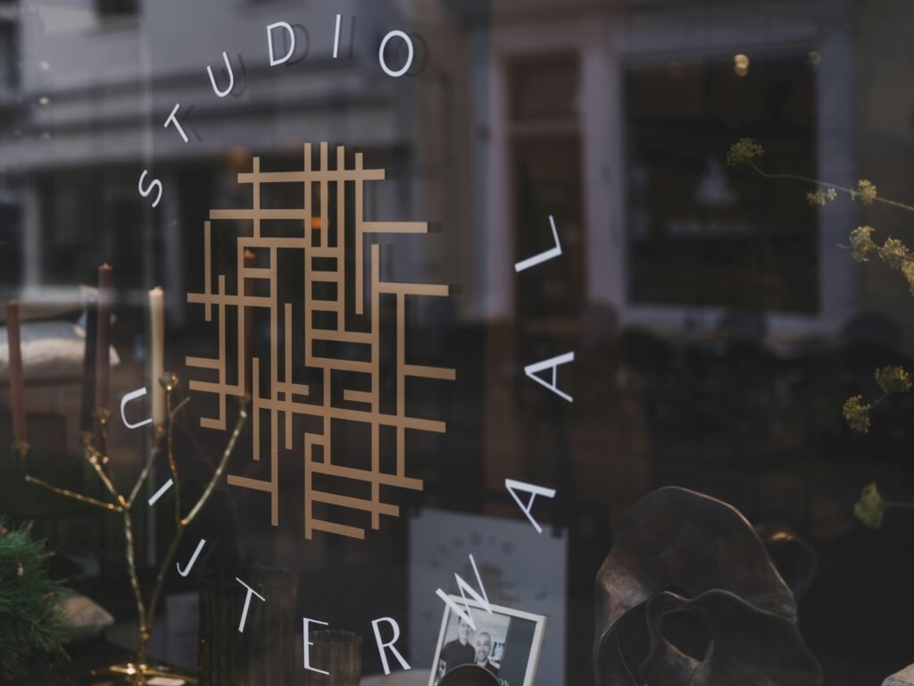 Studio-Logo auf einer Glasfassade mit Spiegelungen der Umgebung – moderne Markenpräsentation im urbanen Kontext