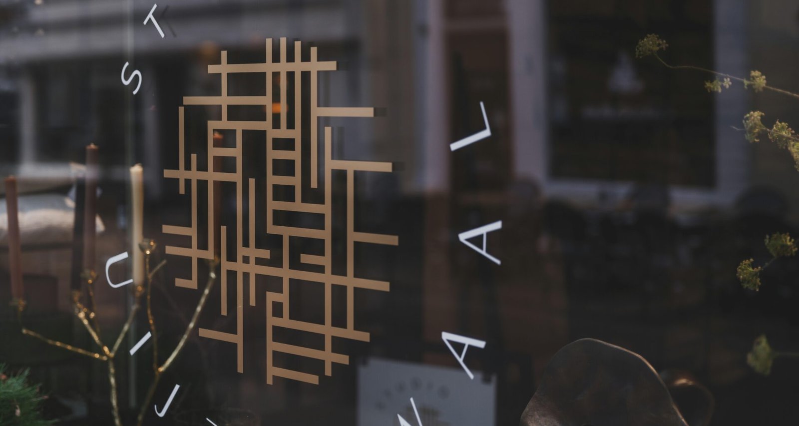 Studio-Logo auf einer Glasfassade mit Spiegelungen der Umgebung – moderne Markenpräsentation im urbanen Kontext