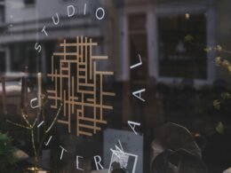 Studio-Logo auf einer Glasfassade mit Spiegelungen der Umgebung – moderne Markenpräsentation im urbanen Kontext