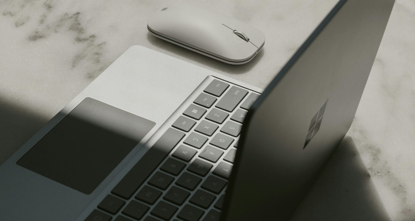 Surface Laptop positioniert neben einer Maus auf einem hellen Schreibtisch, geeignet für digitales Arbeiten und modernes Büroambiente