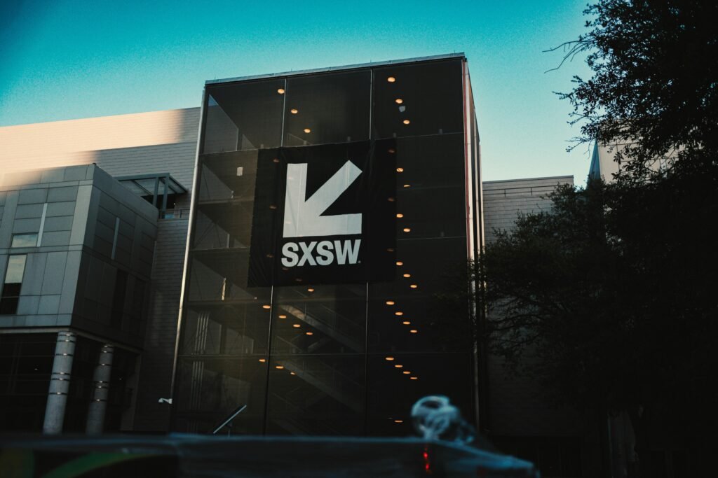 Das SXSW-Gebäude mit großem Logo vor strahlend blauem Himmel, modernes Design und klare Linien in Austin