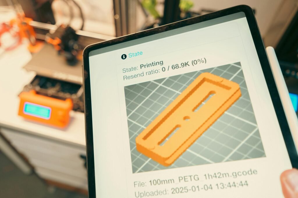 Tablet zeigt den Fortschritt eines 3D-Drucks mit laufendem 3D-Drucker im Hintergrund unter Einsatz moderner Technik.