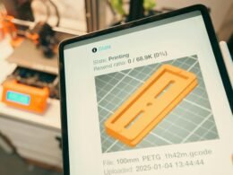 Tablet zeigt in Nahaufnahme live den Fortschritt eines 3D-Drucks, im Hintergrund ist der 3D-Drucker sichtbar