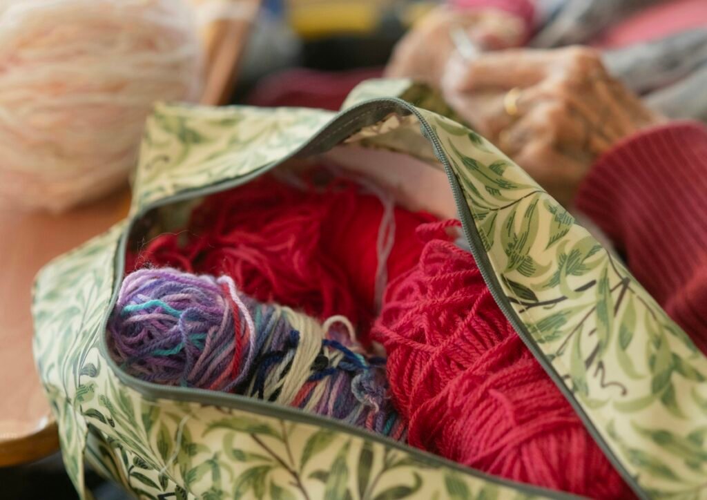Gefüllter Beutel mit verschiedenen farbigen Garnknäueln und Strickzubehör, fotografiert für einen Technik- und Kreativartikel
