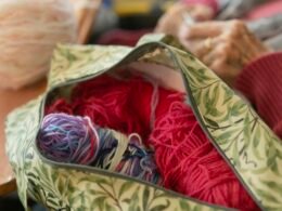 Gefüllter Beutel mit verschiedenen farbigen Garnknäueln und Strickzubehör, fotografiert für einen Technik- und Kreativartikel