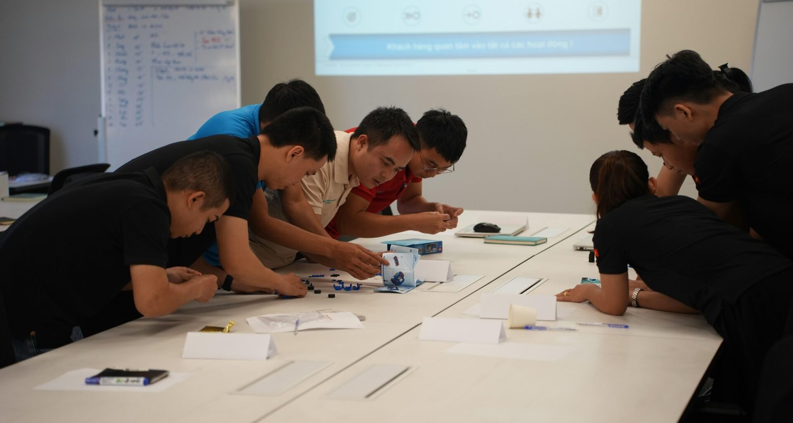 Mehrere Menschen sitzen an einem Tisch und arbeiten gemeinsam an Unterlagen und Laptops an einem Projekt