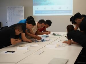 Mehrere Menschen sitzen an einem Tisch und arbeiten gemeinsam an Unterlagen und Laptops an einem Projekt