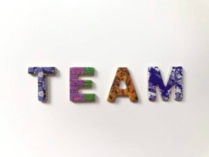 Freistehende Buchstaben, die das Wort Team bilden, symbolisieren Teamarbeit auf einem hellen Untergrund.