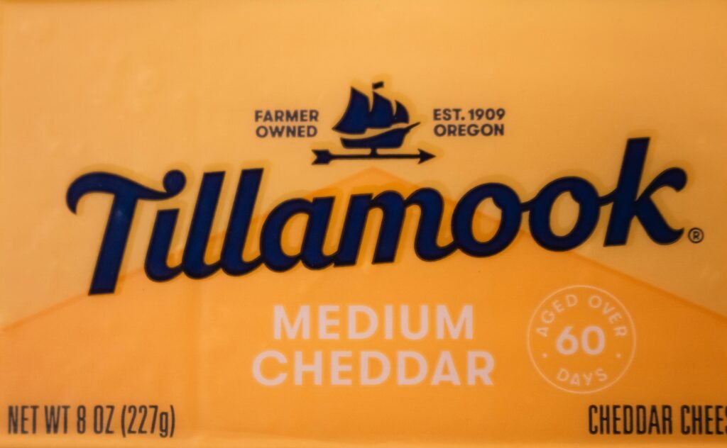 Mittelgereifter Tillamook Cheddar Käse auf hölzernem Untergrund in Scheiben geschnitten, detailreiche Nahaufnahme