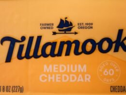 Mittelgereifter Tillamook Cheddar Käse auf hölzernem Untergrund in Scheiben geschnitten, detailreiche Nahaufnahme