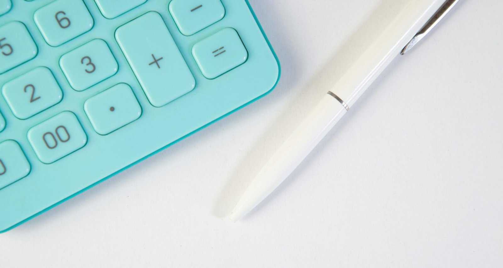 Türkiser Taschenrechner und weißer Stift liegen auf weißem Hintergrund für Themen wie Online-Marketing und digitales Arbeiten
