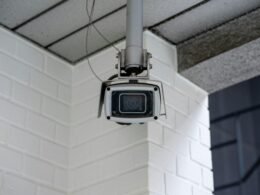 Sicherheitskamera ist an einer weißen Backsteinwand montiert und überwacht den Bereich vor der Wand.