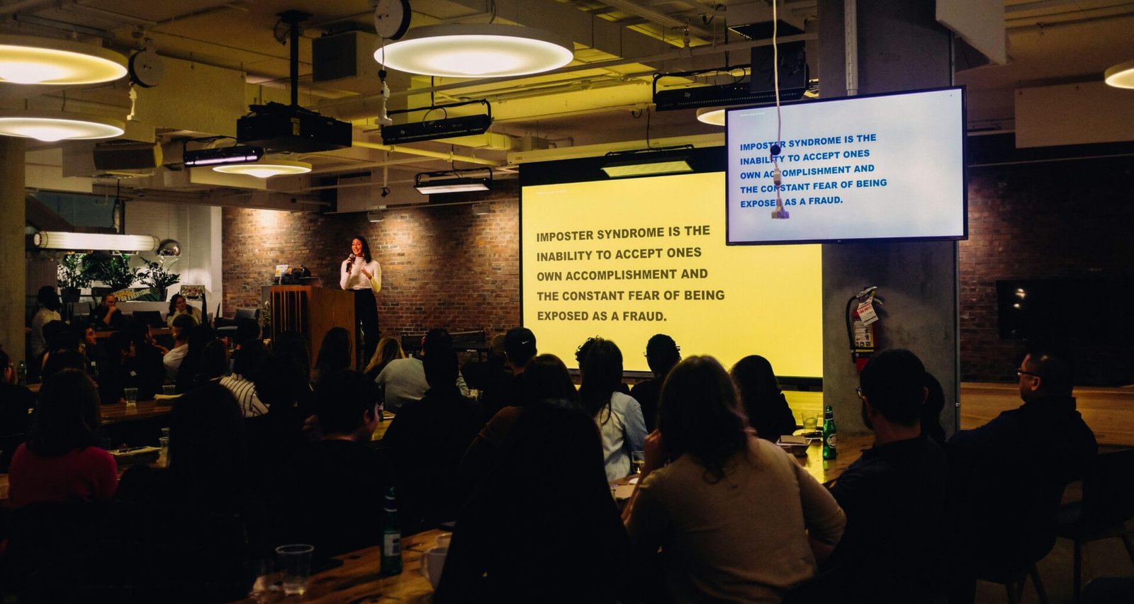 Unbekannte Personen sitzen gemeinsam an einem Tisch in einem hellen, modernen Innenraum und arbeiten zusammen.