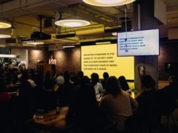 Unbekannte Personen sitzen gemeinsam an einem Tisch in einem hellen, modernen Innenraum und arbeiten zusammen.