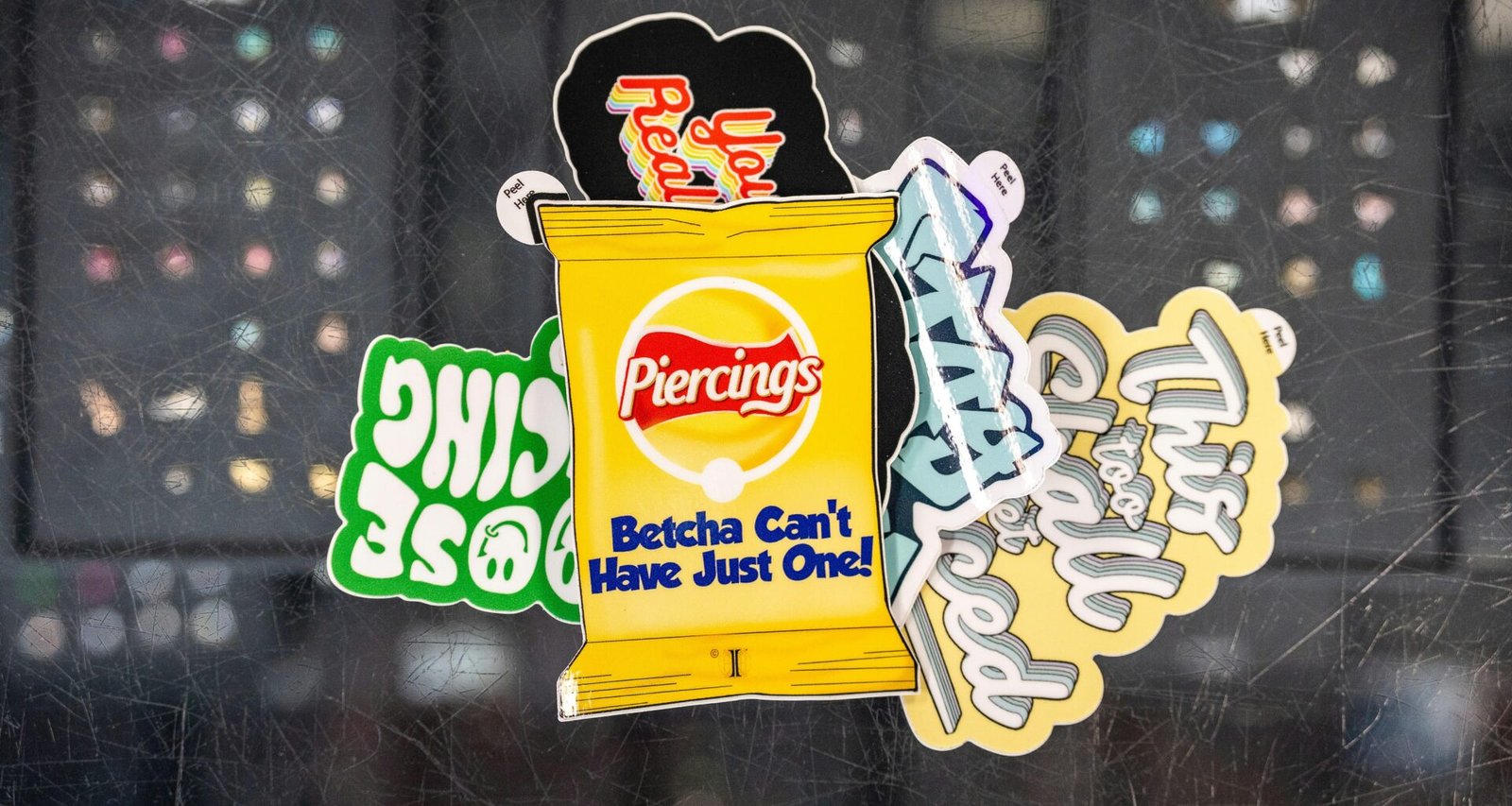 Verschiedene bunte Sticker, darunter ein Design einer Kartoffelchip-Tüte, arrangiert auf heller Oberfläche