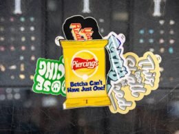 Verschiedene bunte Sticker, darunter ein Design einer Kartoffelchip-Tüte, arrangiert auf heller Oberfläche