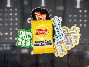 Verschiedene bunte Sticker, darunter ein Design einer Kartoffelchip-Tüte, arrangiert auf heller Oberfläche