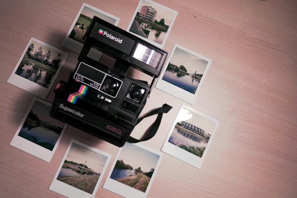 Verschiedene Fotos rund um eine Polaroid-Kamera auf einem Tisch, dargestellt aus der Draufsicht