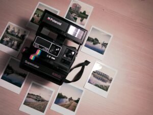 Verschiedene Fotos rund um eine Polaroid-Kamera auf einem Tisch, dargestellt aus der Draufsicht
