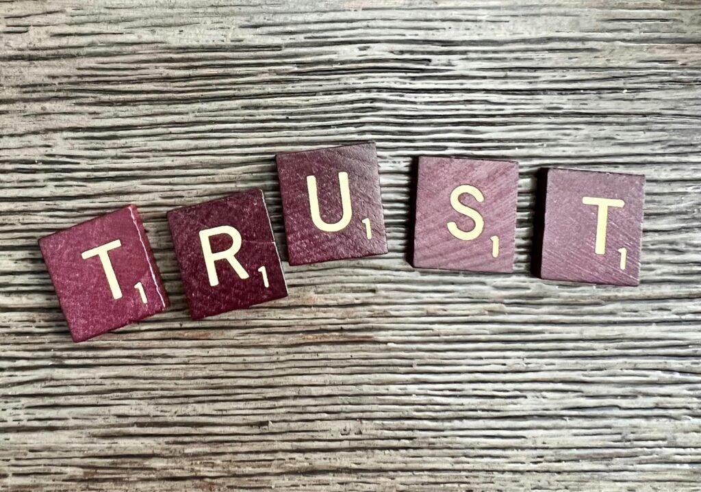 Holzbuchstaben, die das Wort Trust auf einer glatten Tischoberfläche bilden, fotografiert aus der Nähe
