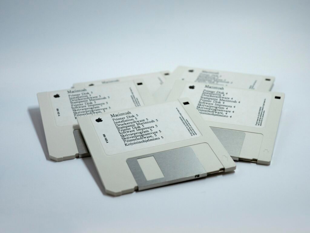 Vier übereinanderliegende klassische MacBook-Disketten als Symbol für frühere Speichertechnologien auf einem hellen Untergrund