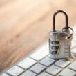 Nahaufnahme von Vorhängeschloss und Schlüsseln auf einer Computertastatur als Symbol für IT-Sicherheit und Datenschutz